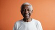 © Arceli - mixed race elderly man orange background wearing plain white tshirt smiling happy portrait