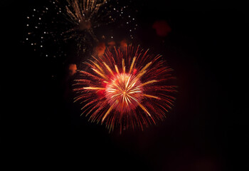 Poster - An isolated firework explodes in a burst of red and yellow against a black background.