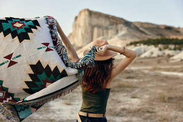 Wall Mural - Woman standing with blanket in front of majestic mountain and valley scenery