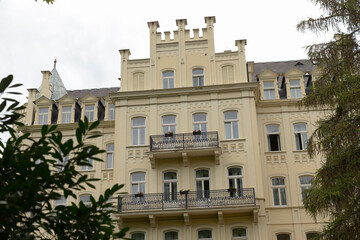 A very large building featuring a spacious balcony and beautiful trees located right in front of it, adding charm to the scene