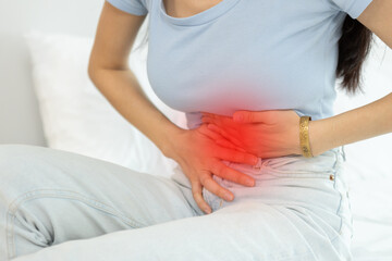 woman sitting on bed stomach ache. Have stomachache, menstrual disorders, food allergies, food poisoning, body aches and pains.  gastritis, diarrhea, enteritis.