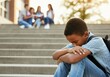 © Alexandra - Elementary age boy is sitting alone on the stairs outside school feeling sad and excluded