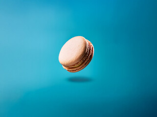 Aufkleber - A single macaron with a light yellow filling hovers against a blue background.