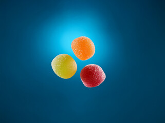 Poster - Three colorful, round candies with a grainy texture hover against a blue background.