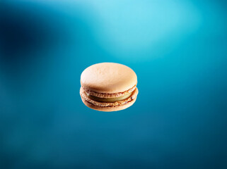 Aufkleber - A single macaron with a creamy filling sits against a blue background.