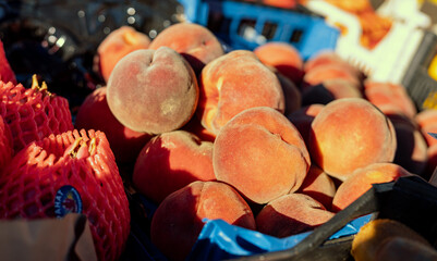 Wall Mural - Farm fresh peaches on display in the morning sun at a local farmers market.