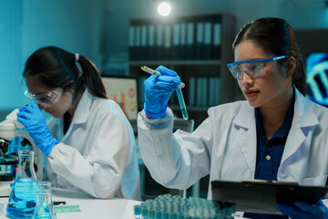 Two scientists working in a laboratory, one holding a test tube and the other using a microscope