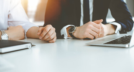 Unknown business people using laptop computer at the desk in modern office. Businessman or male entrepreneur is working with his colleague. Teamwork and partnership concept