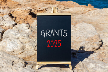 Planning grants 2025 new year symbol. Concept words Grants 2025 on beautiful yellow chalk blackboard. Beautiful stone beach blue sky background. Business grants 2025 new year concept. Copy space.