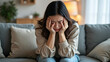 © yarku20 - A young woman seated on a soft couch displays visible signs of distress and emotional pain, holding her head in her hands, reflecting the struggles of mental health and the need for support