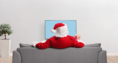 Poster - Rear view shot of Santa claus watching tv and eating popcorn at home