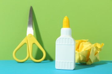 Sticker - Bottle of glue, crumpled paper and scissors on color background, closeup