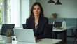 © Photo Collection - Business woman in checkered jacket with smile while sitting at desk in her office.