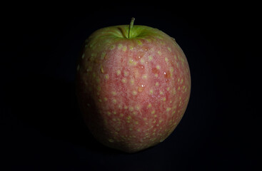 One fresh kissabel apple fruit. Naturally pink flesh with a unique zesty taste in minimalist style on dark background. Light and Shadow, Space for text, Selective Focus.