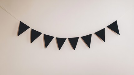 Poster - A Halloween banner with simple geometric black shapes on a white string, hanging against a plain wall for a subtle festive touch