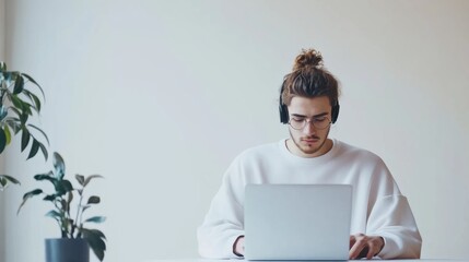 Leinwandbilder - The young freelancer is engaged in remote work at a laptop in a clean, white environment, wearing headphones and concentrating. Generative AI