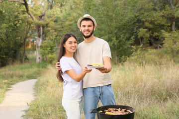 Wall Mural - Young couple cooking food on grill at barbeque party