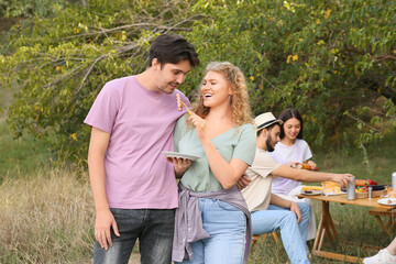 Wall Mural - Young couple eating grilled sausage at barbeque party