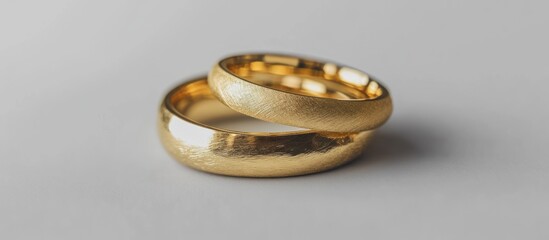 Two gold wedding bands, one on top of the other, on a white background.