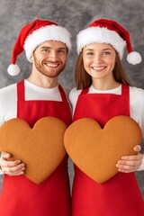 Poster - A cheerful couple in Christmas attire holding heart-shaped cookies.