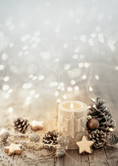 white christmas candle on rustic wooden boards - decoration with natural elements, twigs, pine cones