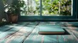 © Dulemegapixel - A serene image showing a closed blue book resting on a distressed turquoise wooden surface, with sunlight filtering through a nearby window, invoking calm and creativity.