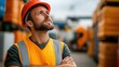 © LifeMedia - A construction worker wearing an orange safety vest and hard hat looks upward, surrounded by blurred construction materials, capturing a moment of focus and determination.