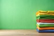 © Latsamee - Stack of fresh colored clothes on green background with empty copy space, minimalist style