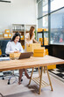 © Phushutter - Two young female entrepreneurs work together in warehouse with parcel boxes, wooden tables, and shelves. prepare sales brochures, social media templates, business proposals for small online business.