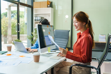 Two young female business consultants work on startup, collaborating on mobile app development social media strategies. whiteboards, documents, they aim to build a successful e-commerce business.
