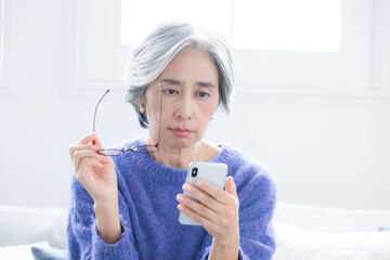 Poster - スマホを持って画面を見るグレイヘアの高齢者のイメージ　老眼で見えにくいクローズアップ