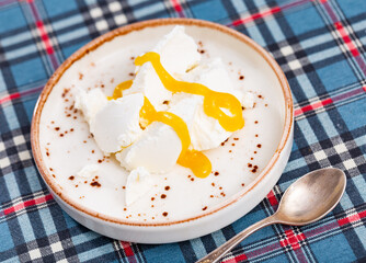 On ceramic plate, portion of grainy cottage cheese sweetened with transparent yellow honey