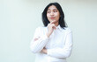 © M Alfan Setyawan - studio shot of happy pleased asian business woman manager thinking idea with hands on chin and arms folded looking away imagine, wearing white formal suit shirt standing isolated, advertising