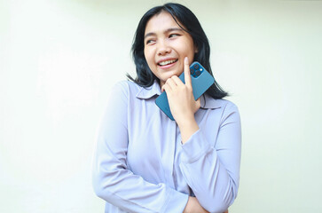 portrait of thoughtful positive asian young business woman holding cell phone thinking plan with dreamy face, daydreaming female wear formal shirt using social media isolated over white background