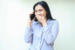© M Alfan Setyawan - portrait of attractive asian business woman speaking on smartphone covering mouth with hand laughing shy feeling embarrassed looking away standing over isolated white background wear formal shirt