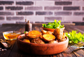 Poster - baked potato wedges with spices and rosemary on a wooden background