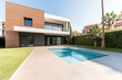 © JuanM - Modern house with pool and garden in a sunny suburban area during daytime