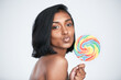 © peopleimages.com - Model, lollipop and portrait for skincare, beauty and wellness, health or diet on white background. Woman pout, smile and confectionary for sweet snack or candy for body care or dermatology in studio