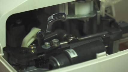 Poster - A woman carefully applies lubricant to the intricate components of a sewing machine, ensuring each part runs smoothly and efficiently during stitching tasks. Vertical video