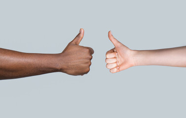 African man hand showing thumb up. Caucasian woman hands showing thumbs up. Black and white thumbs up. Closeup of female and man hands doing thumbs up. Black and white hands showing like together