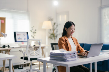 Poster - Confident asian businesswoman works happily on her laptop in a modern office, embodying professionalism and success