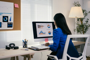 Poster - Focused young businesswoman analyzing data on computer in modern office, embodying dedication and determination