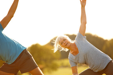 Yoga, class and mature woman with stretching in park for exercise, balance and mobility in nature. Outdoor, people and together on field for arm workout, holistic wellness and mockup with pilates