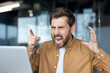 © Liubomir - Frustrated businessman yelling at laptop during video call. Intense anger and stress evident in facial expressions. Office setting hints at workplace conflict, emotion, frustration, and tension.