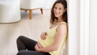 © Anne/peopleimages.com - Portrait, house and pregnant woman on floor, wellness and relax with break, care and stomach. Face, person and mother on ground, calm and routine with happiness, pregnancy and healthy lady in lounge