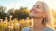 © mangolovemom - A serene woman with gray hair smiles joyfully outdoors, basking in sunlight amidst a field of flowers.