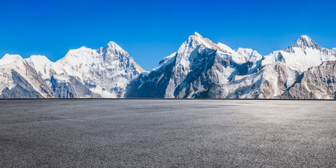 Wall Mural - asphalt road square and snow mountain natural landscape under blue sky. car background.