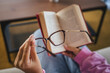 © Lana Milanovic - unknown woman sit on sofa read book and hold eyeglasses