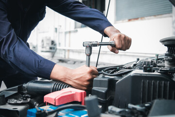 Mechanic using wrench while working on car engine outside the service center , Repair and service.