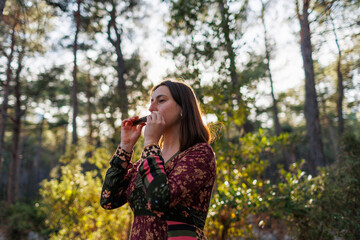 young girl plays the harmonica in the forest. the girl loves to play the harmonica.